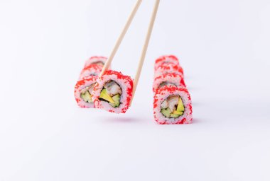 Beyaz arkaplanda yemek çubukları olan Japon uramaki.