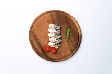 Çeri domatesli tuzlu uskumru dilimleri ve ahşap doğrama tahtasında roka yaprağı. 