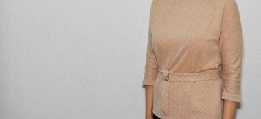 Duvarda sıradan kıyafetler giyen bir kadın. 