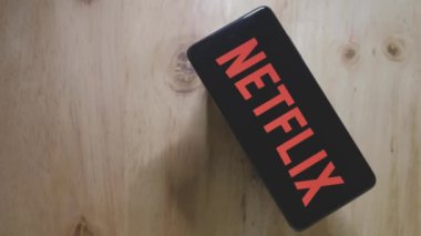Akıllı telefondaki Netflix logosu. Netflix logolu bir masa ve sıcak bir fincan kahve. Netflix logosu üzerine sıcak kahve buharı bir Android Smartphone üzerine yansıtılıyor.