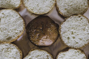 Kesme tahtasına yerleştirilmiş hamburger ekmeği. Hamburger yapmak için dilimlenmiş ekmek dilimleri ve susam tohumlarıyla tahta kesmek. Kızarmış et ya da et için susamlı sandviç. Üstünde marul olan sandviçler..