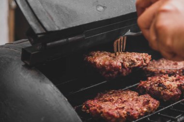 Izgarada hamburger ve etin üstünde erimiş peynir var. Et ızgarada ve kömürde pişiyor. Pişirmek için et ısısı. Hamburger için ızgara et. Domuz sandviçi. Siyah gri üzerinde domuz pişirmek