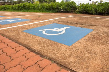 Betondaki engelli park yerinin ayrıntıları. Yerde mavi beyaz bir tabela var.