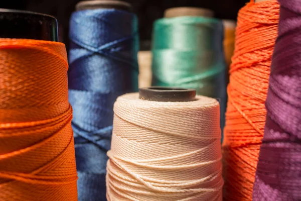 Çoklu renkli makaralar ve çizgi konileri. Mavi, turuncu, mor, yeşil, beyaz iplikler.