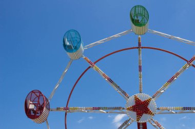 Mavi gökyüzünde üç koltuklu Big Wheel yaz günü bir lunaparkta.