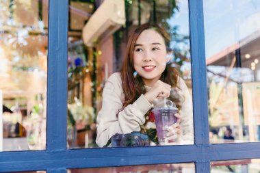 Güzel bir kadın bir kafede içmekten ve içmekten zevk alıyor. Aynadaki yansımalarla birlikte.