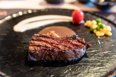 Siyah tabakta ızgara wagyu bifteği ve sebze.