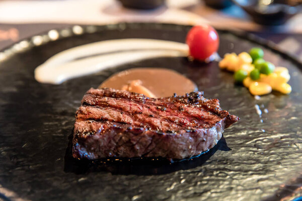 Grilled wagyu beef steak with  vegetables on a black plate