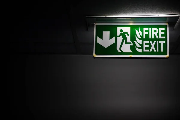 Green fire exit sing in darkness, emergency way