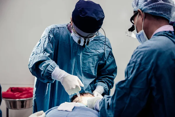 Doctor with surgical tools making surgery in the operating room, baldness treatment, hair transplant