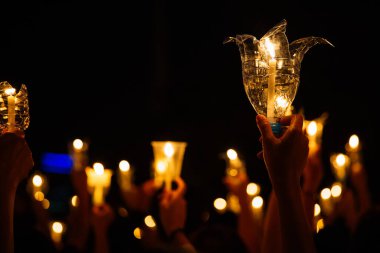 Dua etmek için elinde mum tutan insanlar