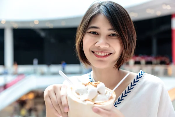 Coconut ice cream in coconut shell in woman hands enjoying eating, Thailand street food