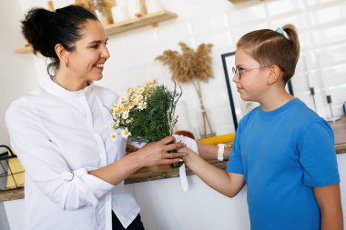 Oğlan annesine bir buket papatya verir..