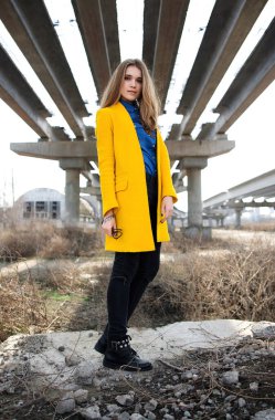 Terk edilmiş bir şantiyede sarı ceketli genç bir kız. şehir manzarası.