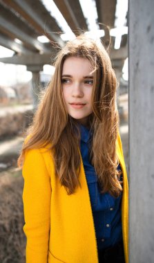 Terk edilmiş bir şantiyede sarı ceketli genç bir kız. şehir manzarası.