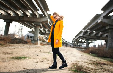 Terk edilmiş bir şantiyede sarı ceketli genç bir kız. şehir manzarası.