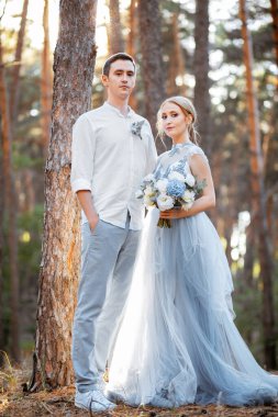 Ormanda ve göl kenarında akşam yürüyüşüne çıkmış mutlu genç bir çift. Gelin mavi bir gelinlik giyiyor..