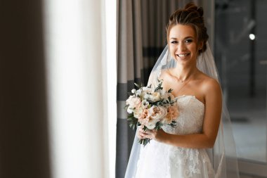 Düğün günü elinde bir buket çiçekle mutlu bir gelinin portresi.