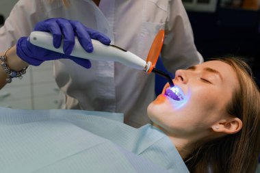 Diş hekimi hastaya diş teli takar. Yakın plan.