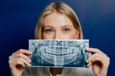 Elinde mavi arka planda röntgen olan bir dişçi..