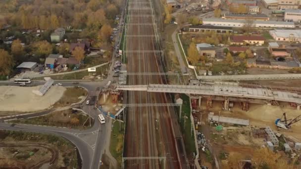 A suburban train passes under a new road bridge under construction in autumn. — Stock Video