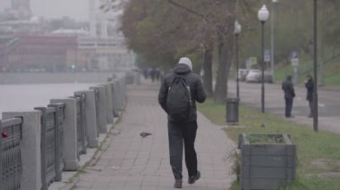 Genç adam sonbaharda Moskva Nehri 'nin seti boyunca yürür.