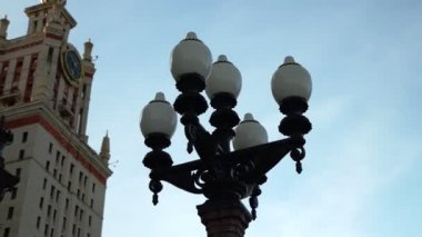 Moskova Devlet Üniversitesi girişinde dört lamba bulunan siyah sokak lambası.