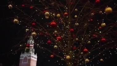 Gece Moskova Kremlin 'inin arka planında bir ağacın üzerindeki parlak yeni yıl süslemeleri. Elden çıkarıldı. 2020. Oyuncak bebek kamerası.
