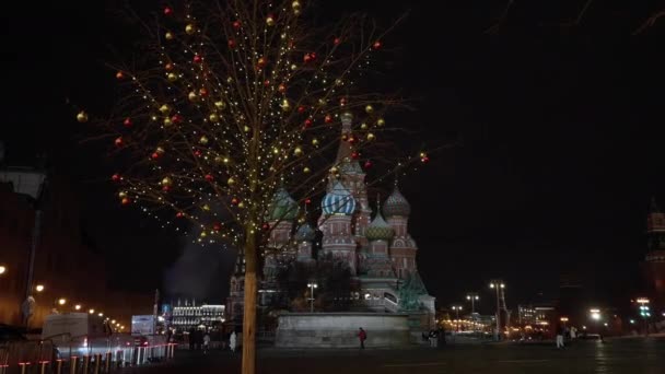 Decorações de Ano Novo brilhantes em uma árvore contra o fundo do Kremlin de Moscou à noite. removido das mãos. 2020. dolly câmera tiro — Vídeo de Stock