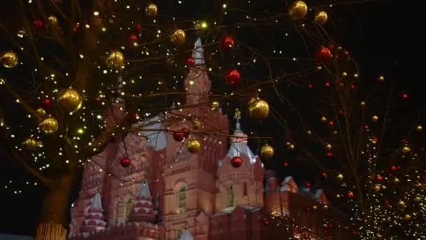 夜晚，在莫斯科克里姆林宫的背景下，树上挂着明亮的新年装饰品。手下留情。2020.玩具娃娃相机拍摄 — 图库视频影像