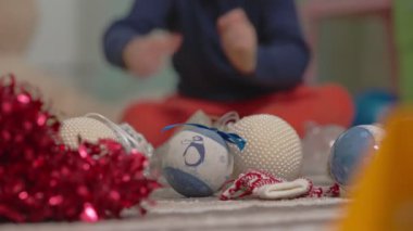 Bir çocuğun eli, bebek odasının zemininden mavi beyaz bir Noel ağacı oyuncağı alır. Yakın plan. seçici odak