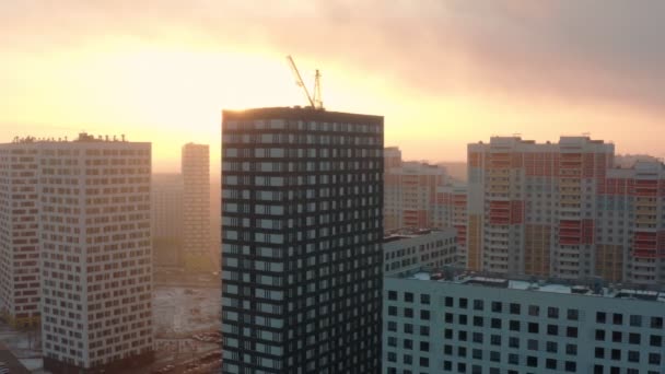 Proces výstavby moderní obytné čtvrti s věžovým jeřábem při východu slunce. letecký pohled. jasné sluneční světlo — Stock video