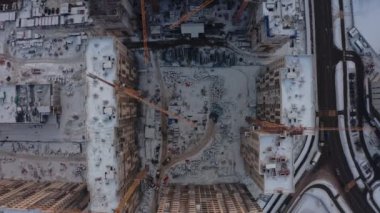 Kışın modern evler inşa etme süreci. Birkaç sarı turna kuşu, karlı bir günde kışın modern evler inşa eder. İnşaatçılar üstte. hava görünümü