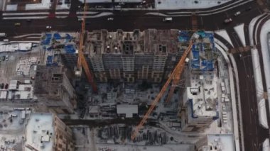 Kışın modern evler inşa etme süreci. Birkaç sarı turna kuşu, karlı bir günde kışın modern evler inşa eder. İnşaatçılar üstte. hava görünümü