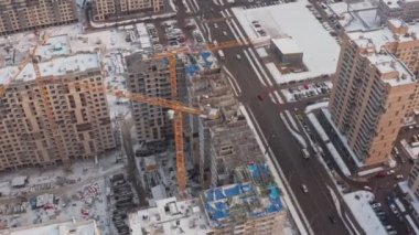 Kışın modern evler inşa etme süreci. Birkaç sarı turna kuşu, karlı bir günde kışın modern evler inşa eder. İnşaatçılar üstte. hava görünümü