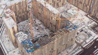 Kışın modern evler inşa etme süreci. Birkaç sarı turna kuşu, karlı bir günde kışın modern evler inşa eder. İnşaatçılar üstte. hava görünümü