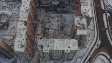 Kışın modern evler inşa etme süreci. Birkaç sarı turna kuşu, karlı bir günde kışın modern evler inşa eder. İnşaatçılar üstte. hava görünümü