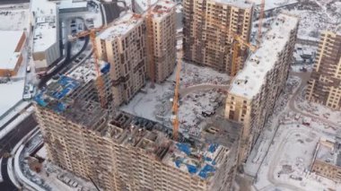 Kışın modern evler inşa etme süreci. Birkaç sarı turna kuşu, karlı bir günde kışın modern evler inşa eder. İnşaatçılar üstte. hava görünümü