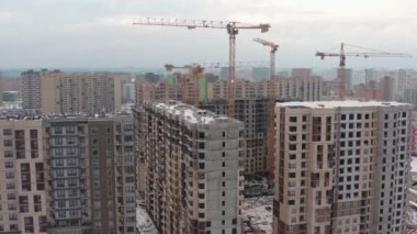 Kışın modern evler inşa etme süreci. Birkaç sarı turna kuşu, karlı bir günde kışın modern evler inşa eder. İnşaatçılar üstte. hava görünümü