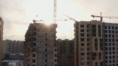 Güneşli bir kış gününde modern bir mahallenin arka planına karşı sarı kule vinçleri olan modern evler inşa etme süreci. hava görünümü