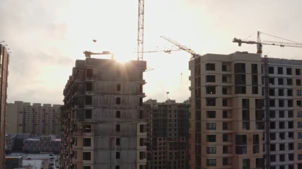 El proceso de construcción de casas modernas con grúas torre amarillas en un día soleado de invierno sobre el fondo de un barrio moderno. vista aérea — Vídeo de stock