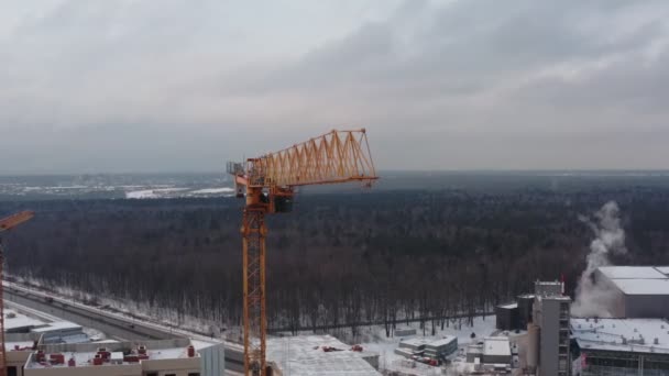 Gele torenkraan aan het werk ter hoogte van een grote bouwplaats tegen de achtergrond van andere torenkranen. zicht van bovenaf — Stockvideo