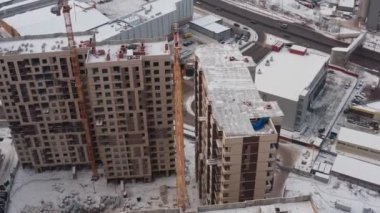 Sarı kule vinci, diğer vinçlerin arka planına karşı büyük bir inşaat alanının yüksekliğinde çalışıyor. Yukarıdan görünüm