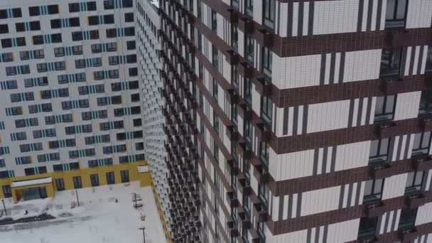 Novo edifício moderno de arranha-céus preto e branco contra o pano de fundo de uma área residencial colorida no inverno. vista aérea — Vídeo de Stock