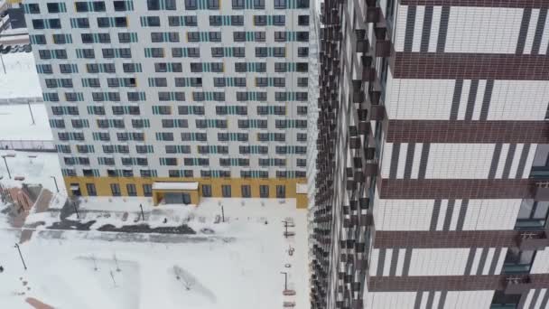 在一个五彩缤纷的冬季住宅区的背景下，新建了一座现代的黑白高层建筑。航拍视图 — 图库视频影像