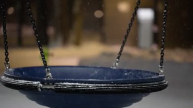 Yoğun bir kar yağışı sırasında tamamen boş bir oyun alanında sallanmak. Covid-19 salgını sırasında. Yavaş çekim