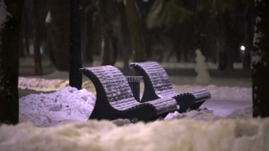 Gece yoğun kar yağarken parktaki boş sokak bankları. Pandemik tecrit sırasında