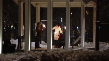 Çocuklu genç bir aile akşamları parktaki bir çardakta maytaplarla eğleniyor.