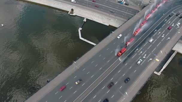 Flera speciella vattningsmaskiner, uppradade i rad, häller vatten på bron på en av huvudgatorna i Moskva. Flygbild — Stockvideo