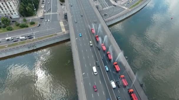 Αρκετές ειδικές μηχανές ποτίσματος, παρατεταγμένες στη σειρά, ρίχνουν νερό στη γέφυρα ενός από τους κεντρικούς δρόμους της Μόσχας. Αεροφωτογραφία — Αρχείο Βίντεο